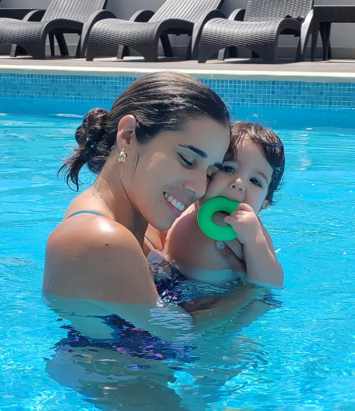 Gissel Giménez abrazando a un alumno pequeño dentro de la piscina